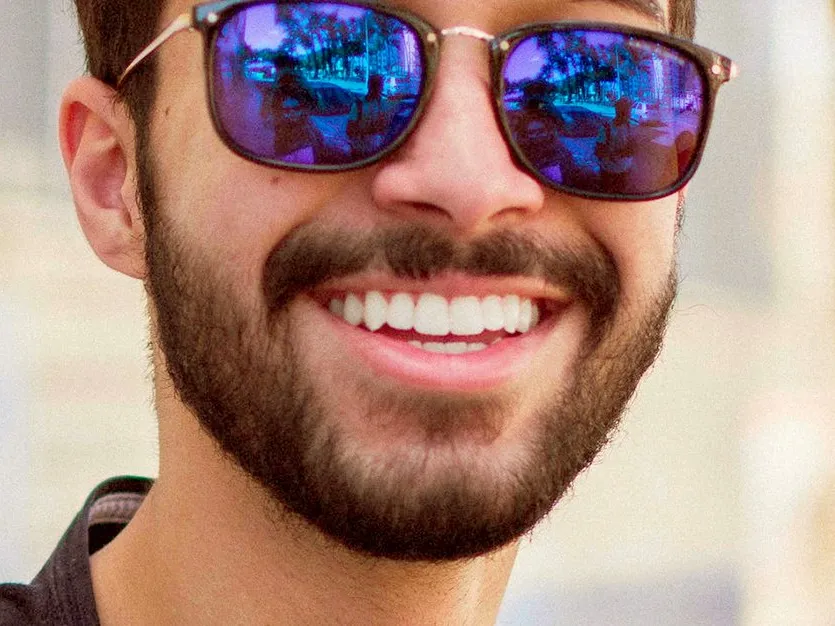 A man in sunglasses with a wide, white smile.
